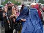 Women walk through the old market as a Taliban fighter stands guard, in the city of Kabul, Afghanistan, Women walk through the old market as a Taliban fighter stands guard, in the city of Kabul, Afghanistan,