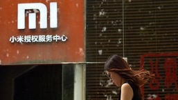 Uma mulher passa por um logotipo da Xiaomi do lado de fora de um centro de serviços da Xiaomi em Pequim.