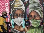 A man walks past a mural by Senzart911 that shows people wearing facemasks at Soweto's Kliptown, South Africa.(Reuters)