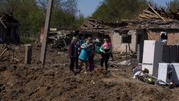 Pessoas reagem ao lado de uma cratera em área residencial destruída após ataque aéreo russo em Bakhmut, região de Donetsk, Ucrânia, em 7 de maio de 2022.