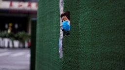 Um morador olha através de uma lacuna na barreira em uma área residencial durante o bloqueio, em meio à pandemia da doença por coronavírus (Covid-19), em Xangai, China.