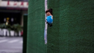 A resident looks out through a gap in the barrier at a residential area during lockdown, amid the coronavirus disease (Covid-19) pandemic, in Shanghai, China. (REUTERS)