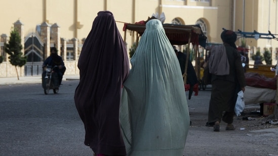 Burqa-clad women walk along a street in Kandahar.(AFP)