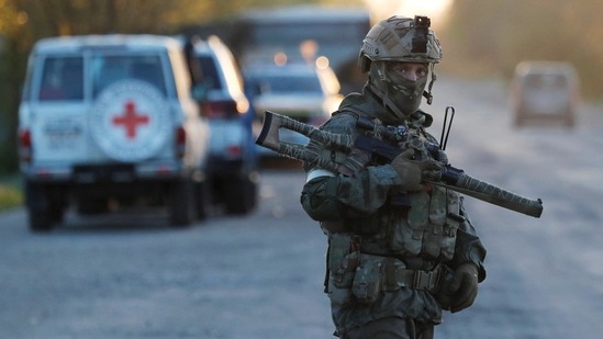 Um membro do serviço de tropas pró-Rússia monta guarda enquanto civis evacuados da siderúrgica Azovstal em Mariupol chegam a um centro de acomodação temporária na vila de Bezimenne, durante o conflito Ucrânia-Rússia na região de Donetsk (REUTERS)