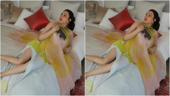 รูปภาพแสดงให้เห็นว่า Kajal กำลังพักผ่อนอยู่บนเตียงในห้องพักของโรงแรมและโพสท่าต่างๆ ให้กับกล้อง  เธอสวมชุดเดรสพิมพ์ลายหลากสีสำหรับโอกาสนี้และจับคู่กับเครื่องประดับแบบมินิมอล (Instagram/@kajalaggarwalofficial)