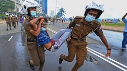 Policemen carry an injured man during a clash between government supporters and demonstrators outside the President's office in Colombo.