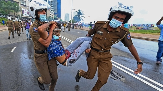 Policemen carry an injured man during a clash between government supporters and demonstrators outside the President's office in Colombo.(AFP)