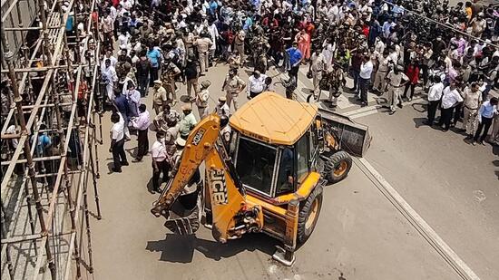 Around 11.30am, when the corporation vehicles and the team of officials started moving towards the market, a huge crowd had gathered on the road. The local residents who alleged ‘selective action’ by the BJP-ruled corporation, sat around the bulldozer. (ANI)