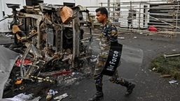 A security personnel walks past a burned vehicle near Sri Lanka's former prime minister Mahinda Rajapaksa's official residence 'Temple Trees', a day after they were torched by protesters in Colombo.
