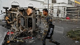 , A security personnel walks past a burned vehicle near Sri Lanka's former prime minister Mahinda Rajapaksa's official residence 'Temple Trees', a day after they were torched by protesters in Colombo.