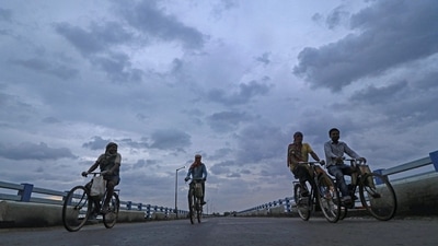 Workers ride their bicycles to return home as dark clouds hover in the skies owing to Cyclone Asani, in Birbhum. (PTI)