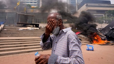 A Sri Lankan man reacts to tear gas as he walks past the vandalized site of anti-government protests outside president's office in Colombo, Sri Lanka, Monday, May 9, 2022.. (AP Photo/Eranga Jayawardena) A Sri Lankan man reacts to tear gas as he walks past the vandalized site of anti-government protests outside president's office in Colombo, Sri Lanka, Monday, May 9, 2022.. (AP Photo/Eranga Jayawardena)