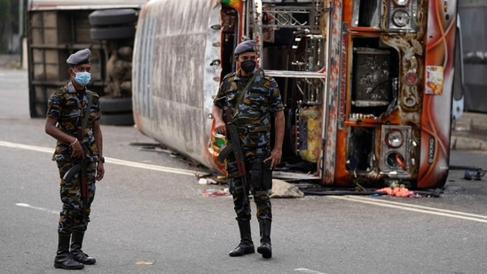 Sri Lankan soldiers stand guard next to burnt buses a day after clashes between government supporters and anti-government protesters in Colombo.(AP)