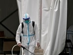 A worker in a protective suit sprays disinfectant at a COVID-19 testing site.