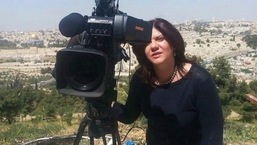 Shireen Abu Aqla, a journalist for Al Jazeera network, stands next to a TV camera.