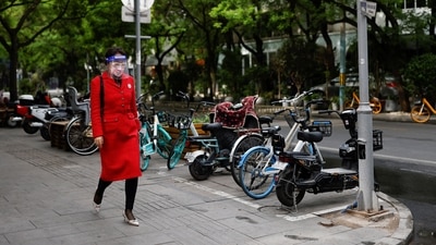 A woman wearing a face mask and a face shield walks down a sidewalk, amid the coronavirus disease (Covid-19) outbreak, in Beijing. (REUTERS)