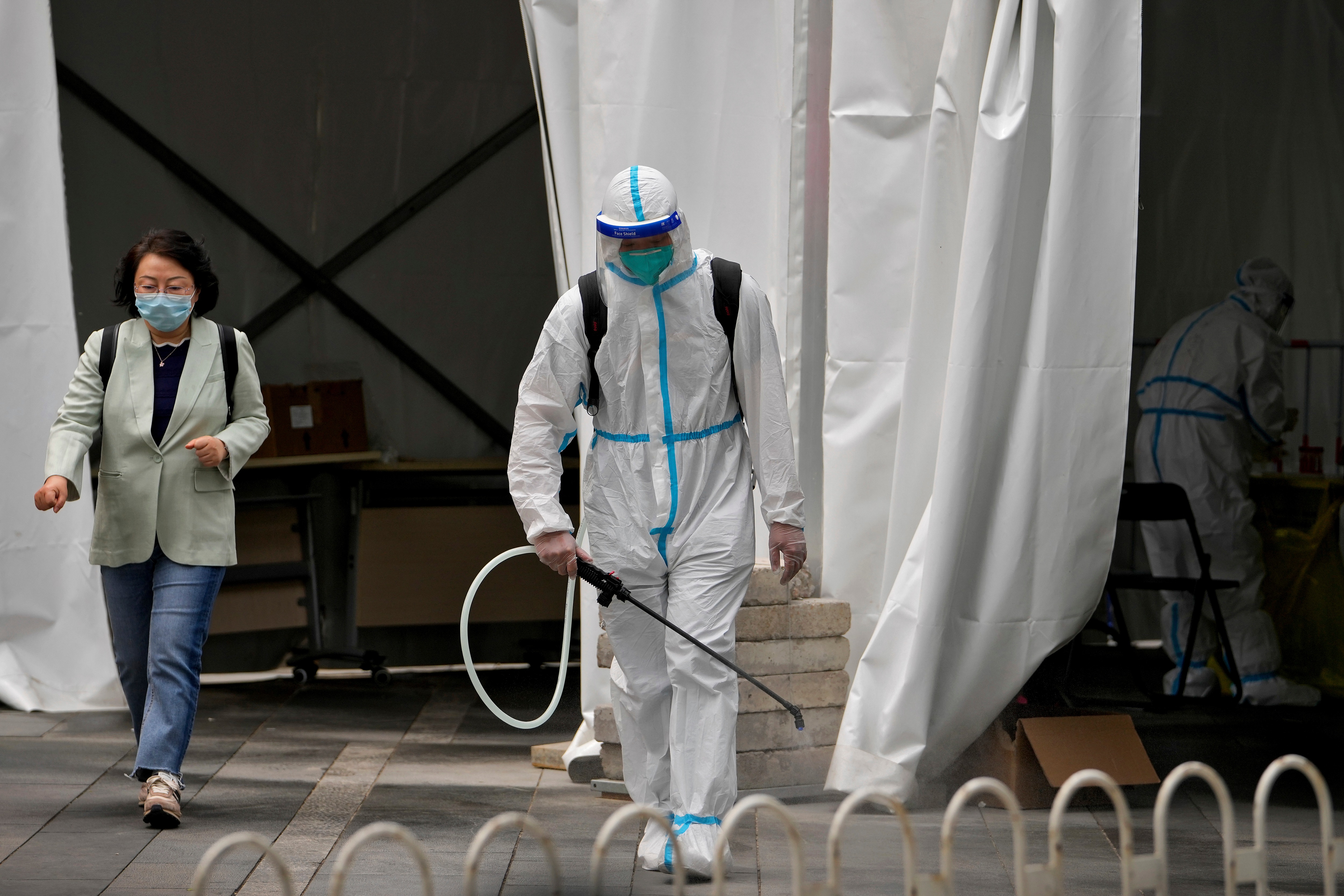 A worker in a protective suit sprays disinfectant at a COVID-19 testing site. (AP file photo)