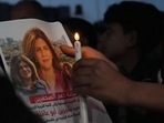 Palestinian holds a light candle and a picture of slain Al Jazeera journalist Shireen Abu Akleh, to condemn her killing, in front of the office of Al Jazeera network, in Gaza City.(AP) Palestinian holds a light candle and a picture of slain Al Jazeera journalist Shireen Abu Akleh, to condemn her killing, in front of the office of Al Jazeera network, in Gaza City.(AP)