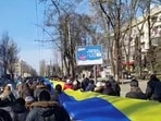 FILE PHOTO: Live-streamed footage shows people carrying a banner in the colours of the Ukrainian flag as they protest amid Russia's invasion of Ukraine, in Kherson, Ukraine in March.&nbsp;