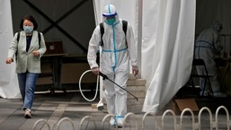 A worker in a protective suit sprays disinfectant at a COVID-19 testing site.