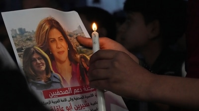 Palestinian holds a light candle and a picture of slain Al Jazeera journalist Shireen Abu Akleh, to condemn her killing, in front of the office of Al Jazeera network, in Gaza City. (AP) Palestinian holds a light candle and a picture of slain Al Jazeera journalist Shireen Abu Akleh, to condemn her killing, in front of the office of Al Jazeera network, in Gaza City. (AP)