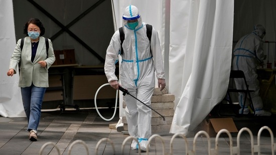 A worker in a protective suit sprays disinfectant at a COVID-19 testing site.(AP file photo)