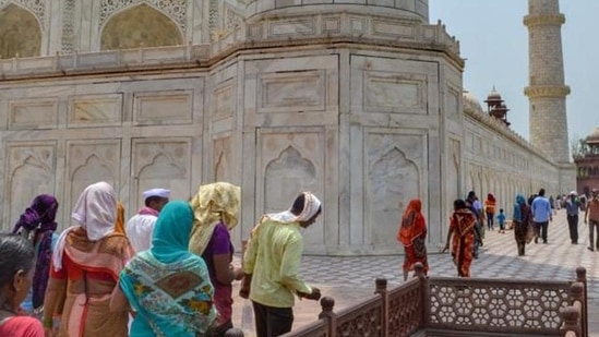 Tourists cover their heads during their visit to the Taj Mahal on a hot summer day, in Agra, Thursday, May 12, 2022. (PTI Photo)