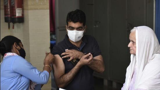 A health worker administers a booster dose of a Covid-19 vaccine to a beneficiary, in Gurugram on Thursday. The city recorded 262 fresh infections on Thursday. (Vipin Kumar/HT PHOTO)