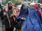 Women walk through the old market as a Taliban fighter stands guard, in the city of Kabul, Afghanistan,(AP)