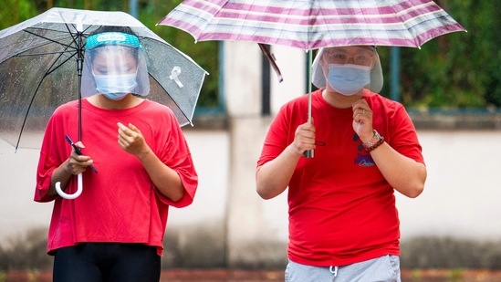 Local residents queue with umbrellas for nucleic acid tests for the Covid-19 coronavirus in a compound under lockdown in the Pudong district in Shanghai on May 13, 2022. &nbsp;(Photo by LIU JIN / AFP)