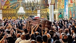 Enlutados palestinos agitam bandeiras nacionais enquanto carregam o caixão de Shireen Abu Aklel dentro de uma igreja, em Jerusalém, 
