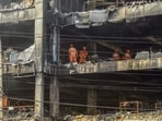 National Disaster Response Force (NDRF) personnel clear the charred debris from a burnt floor a day after a fire broke out in a commercial building at Mundka, New Delhi. (HT PHOTO.)