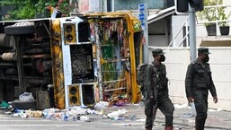 Sri Lankan soldiers walk past a burnt bus near Sri Lanka's former prime minister Mahinda Rajapaksa's official residence