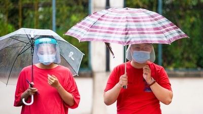 Local residents queue with umbrellas for nucleic acid tests for the Covid-19 coronavirus in a compound under lockdown in the Pudong district in Shanghai. (Photo by LIU JIN / AFP)