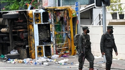 Sri Lankan soldiers walk past a burnt bus near Sri Lanka's former prime minister Mahinda Rajapaksa's official residence (AFP) Sri Lankan soldiers walk past a burnt bus near Sri Lanka's former prime minister Mahinda Rajapaksa's official residence (AFP)