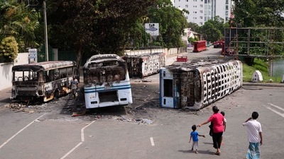 A Sri Lankan family watches the wreckage of buses burnt in clashes in Colombo, Sri Lanka, Wednesday. (AP) A Sri Lankan family watches the wreckage of buses burnt in clashes in Colombo, Sri Lanka, Wednesday. (AP)