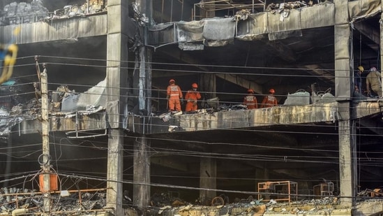 National Disaster Response Force (NDRF) personnel clear the charred debris from a burnt floor a day after a fire broke out in a commercial building at Mundka, New Delhi. (HT PHOTO.)(HT_PRINT)