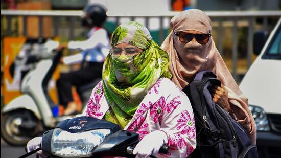 Commuters use scarves to shield themselves from the heat while riding a two-wheeler in Prayagraj. (PTI) Commuters use scarves to shield themselves from the heat while riding a two-wheeler in Prayagraj. (PTI)