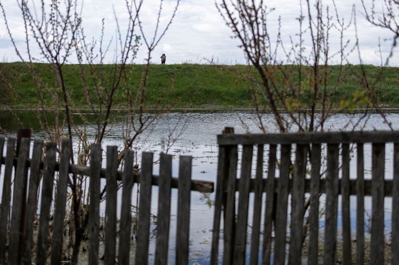 Local residents walk along a flooded area after Ukrainian military forces opened a dam to flood a residential area in order to stop the advance of Russian forces to arrive to the capital city of Kyiv, in Demydiv, Ukraine, May, 15, 2022. (REUTERS/Carlos Barria)