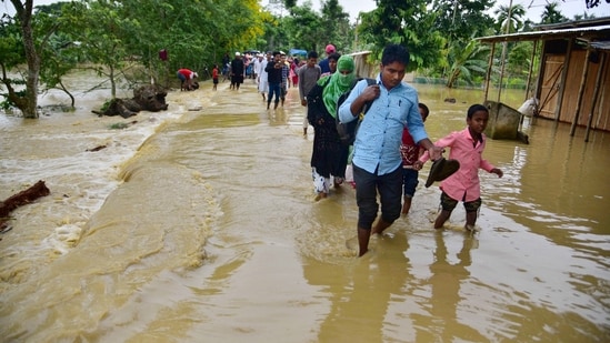 Hojai: Villagers wade through a flood affected area following heavy rains in Hojai district of Assam.(PTI)