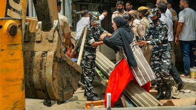 A resident interacts with security personnel during a demolition drive carried out by Delhi Development Authority (DDA) at Khichripur, in New Delhi. (PTI)