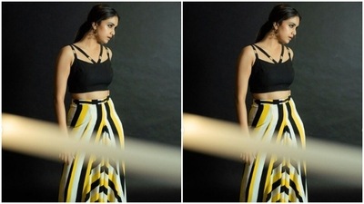 Keerthy decked up in a black cropped top with slip-in sleeves and a strap on the shoulders. She paired it with a long flowy skirt that came in stripes of yellow, black and white. (Instagram/@keerthysureshofficial)