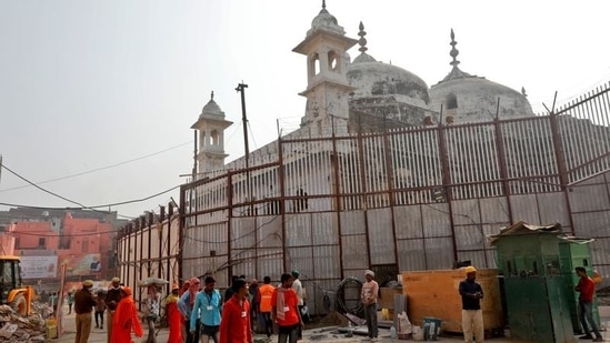 Labourers work in the compound of a temple next to the wall fence of Gyanvapi Mosque.(REUTERS)