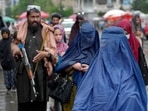 Women walk through the old market as a Taliban fighter stands guard, in the city of Kabul, Afghanistan, Women walk through the old market as a Taliban fighter stands guard, in the city of Kabul, Afghanistan,