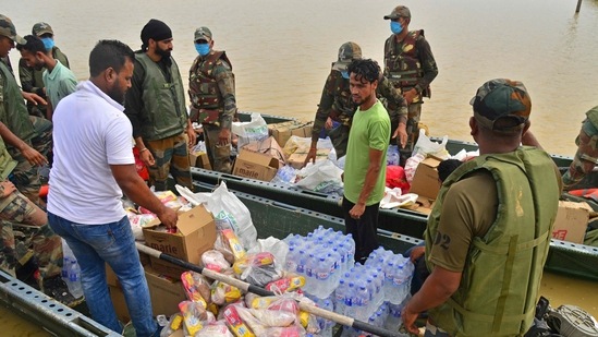 Army soldiers stand in boats carrying relief supplies for the flood-affected villagers after heavy rains in Hojai district of Assam. (AFP)