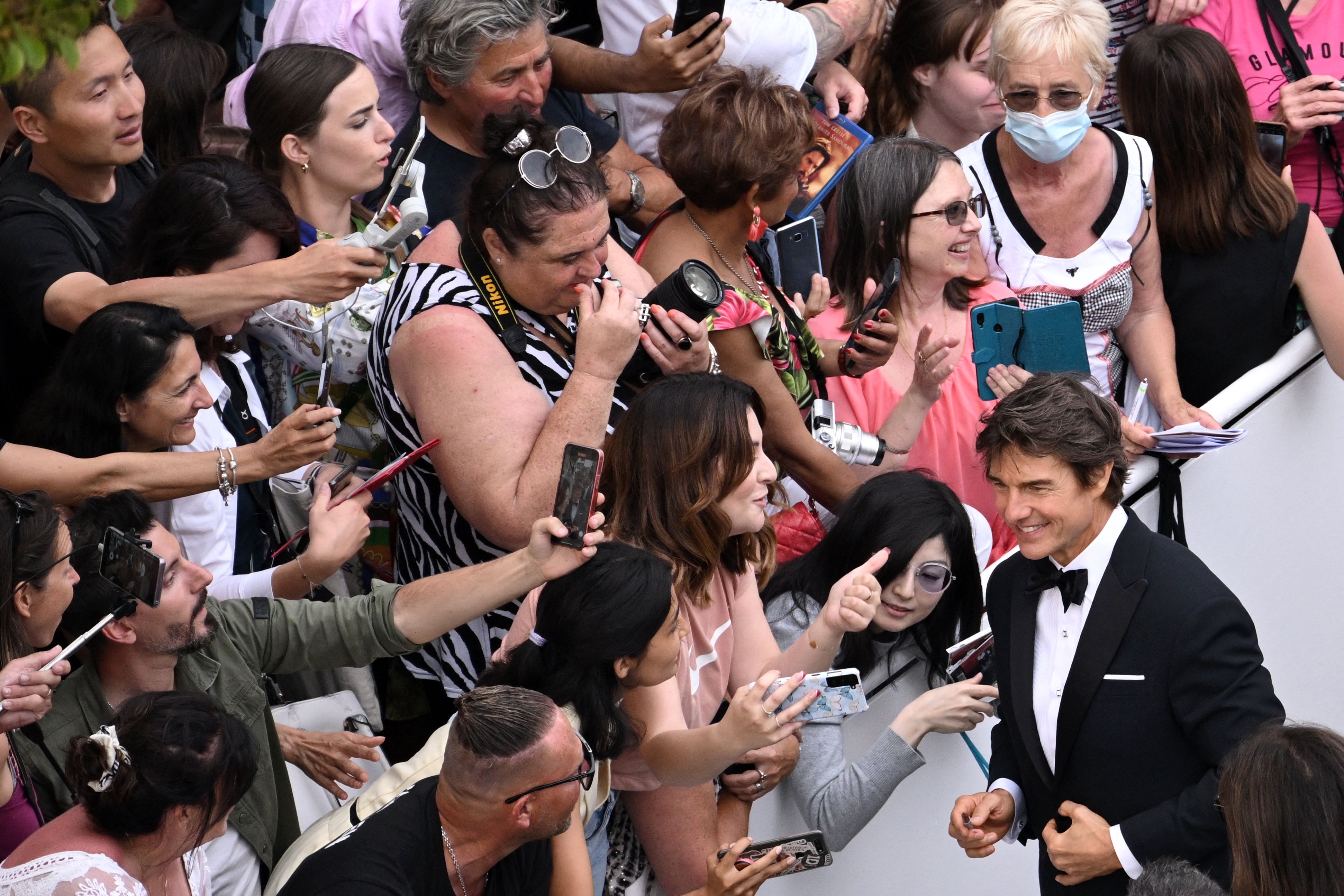 Tom Cruise poses for selfies as he arrives for the screening of the film "Top Gun : Maverick" during the 75th edition of the Cannes Film Festival in Cannes, southern France, on May 18, 2022. (Photo by LOIC VENANCE / AFP)(AFP)