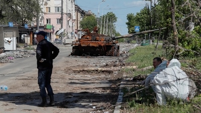 Emergency management specialists gather near a burnt tank during Ukraine-Russia conflict in the southern port city of Mariupol, Ukraine. (REUTERS)