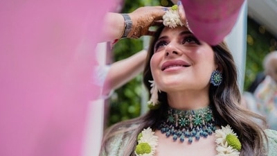 Kanika's Mehendi lehenga set in soothing mint green shade features a cropped blouse with intricate floral lace details and sequinned embroidery. It also comes with a plunging V neckline, scalloped borders, cape-like half sleeves, and a short waistline flaunting the singer's toned midriff. (Instagram) Kanika's Mehendi lehenga set in soothing mint green shade features a cropped blouse with intricate floral lace details and sequinned embroidery. It also comes with a plunging V neckline, scalloped borders, cape-like half sleeves, and a short waistline flaunting the singer's toned midriff. (Instagram)