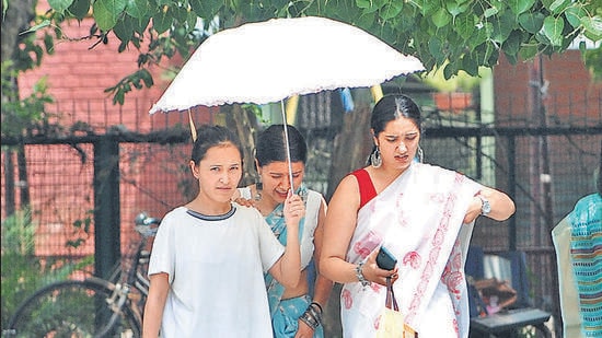 Women taking cover under an umbrella in Sector 11, Chandigarh, on a sweltering Friday afternoon. (Ravi Kumar/HT)
