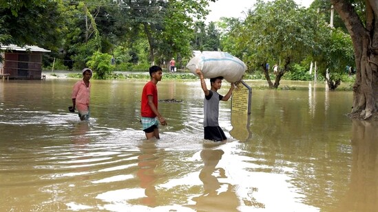 Villagers wade through a waterlogged area following heavy rainfall in Assam's Darrang district. (ANI Photo)
